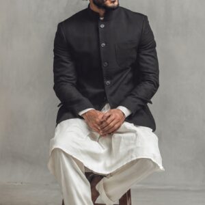Man wearing black sherwani jacket with white traditional outfit in studio fashion portrait